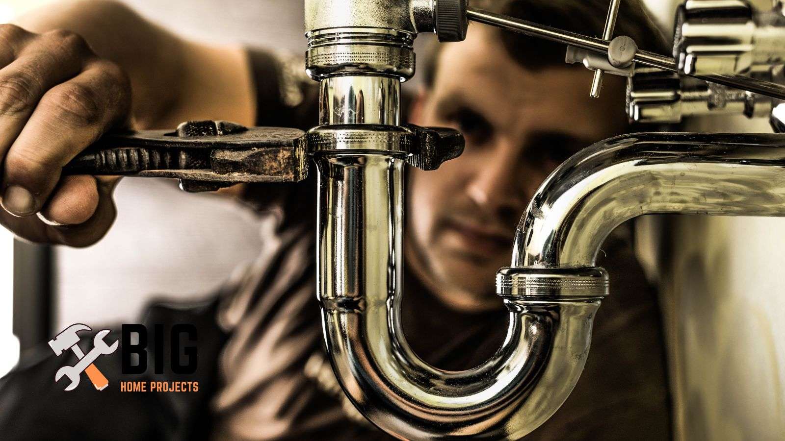 Plumber tightening a pipe - bighomeprojects.com