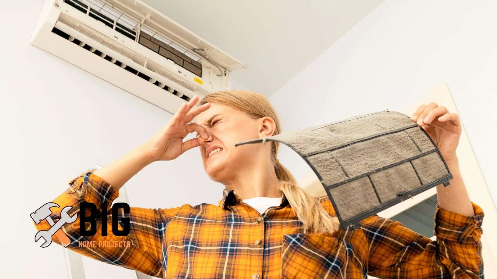 Girl looking at air conditioner filter and it smells bad - bighomeprojects.com
