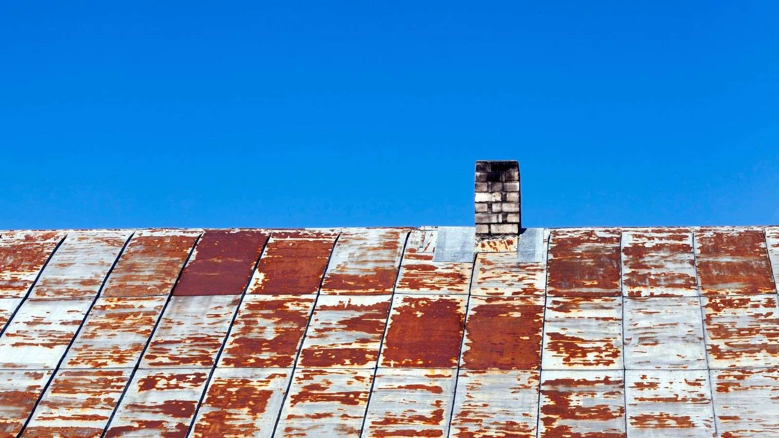 Proper roof maintenance is crucial to the longevity of any building, and handling rusty roofs is a challenge homeowners and maintenance crews often face. The ability to effectively seal such roofs depends on understanding the nature of rust and utilizing the right techniques and products. In this article, we will explore the key methods to properly seal your rusty roof, delve into why rust spreads and how to stop it, and discuss the pros and cons of various solutions, including liquid rubber sealants, silicone sealants, conversion spray treatments, and more. Top 5 Effective Methods to Properly Seal Your Rusty Roof 1. Clean and Treat the Rust Before sealing your rusty roof, you have to clean and treat the rusted areas properly. Start by removing any loose rust, debris, or old coatings using a wire brush or scraper. Next, apply a rust converter or inhibitor to halt the spread of rust. Rust converters chemically react with rust, turning it into a stable surface that can be painted over. This step sets up a solid foundation for the sealant and prevents further rusting. When applying the rust converter, make sure to follow the manufacturer's instructions carefully. Allow sufficient time for the converter to dry and cure before proceeding with the sealing process. 2. Use a High-Quality Waterproof Sealant To successfully seal a roof that has rust, you must use the correct waterproof sealant. Look for a high-quality sealant specifically designed for metal roofs. Opt for sealants with excellent adhesion to metal surfaces and long-lasting waterproofing properties. Silicone-based or polyether-based sealants are commonly recommended for their durability and resistance to moisture and UV exposure. Apply the sealant generously to cover all areas of concern, such as seams, joints, flashing, and any other vulnerable spots where water may penetrate. Use a brush, roller, or sprayer to check for even coverage and proper adhesion. 3. Apply a Reinforcing Fabric To enhance the durability and strength of the sealant, consider incorporating a reinforcing fabric into the sealing process. Reinforcing fabrics, such as polyester or fiberglass mesh, provide an extra layer of protection and help prevent cracking or splitting of the sealant over time. Apply the fabric over the wet sealant and then apply another layer of sealant on top to encapsulate the fabric. Make sure the reinforcing fabric is fully embedded in the sealant, leaving no exposed areas. This will help create a seamless and robust barrier against water infiltration. 4. Consider a Roof Coating System Applying a roof coating system is an effective way to not only seal your rusty roof but also provide additional protection against environmental factors. Roof coatings are available in various formulations, including acrylic, silicone, or elastomeric coatings. These coatings can extend the lifespan of your roof by offering superior waterproofing, UV resistance, and thermal insulation properties. Before applying the roof coating system, thoroughly clean the roof surface, removing any dirt, loose paint, or debris. Follow the manufacturer's instructions regarding application techniques, the number of coats required, and drying and curing times for optimal results. 5. Regular Maintenance and Inspections Once you have successfully sealed your rusty roof, it is essential to perform regular maintenance and inspections to uphold its continued effectiveness. Routinely inspect your roof for any signs of damage, such as cracks, peeling sealant, or areas of rust recurrence. Promptly address any issues by resealing or repairing as necessary to prevent water intrusion. Schedule regular roof inspections at least twice a year and after severe weather events. Clear any debris that accumulates on the roof promptly to prevent water pooling or damage to the sealant. Maintain proper drainage systems to make certain water flows efficiently off the roof surface. Why Rust Spreads and How to Stop It Rust spreads when moisture and oxygen come into contact with iron or steel surfaces, creating a chemical reaction known as oxidation. This process causes the formation of iron oxide, commonly known as rust. Once rust starts to develop, it can continue to spread if left untreated, leading to structural damage and compromised integrity of the affected material. To stop the spread of rust, it is essential to eliminate the conditions that promote its formation. This can be achieved by removing any existing rust through thorough cleaning and then applying protective measures such as rust converters or inhibitors. These products chemically react with the rust, converting it into a stable surface that can be sealed or painted over. Applying a high-quality sealant or coating specifically designed for metal surfaces acts as a barrier, preventing further moisture and oxygen exposure. Finding and fixing any areas susceptible to rust formation before it spreads and causes major damage requires regular maintenance, inspections, and quick repairs. The Problems with Using Flex Seal on Rusty Roofs Inadequate Adhesion: One problem with using Flex Seal on rusty roofs is that it may have inadequate adhesion to the rusty surface. Flex Seal is primarily designed for sealing cracks, leaks, and gaps rather than bonding to corroded metal. Without proper adhesion, the sealant may not effectively create a watertight barrier, which could lead to continued water infiltration. Lack of Rust Prevention: While Flex Seal may temporarily seal the surface and prevent immediate leaks, it does not address the underlying issue of rust formation. Rust will continue to spread unless the rust is eliminated and proper preventive measures are taken. Flex Seal alone does not provide the rust conversion or inhibition properties needed to stop rust from further deteriorating the metal surface. Limited Durability: Flex Seal is typically a temporary solution and may not provide long-lasting durability when applied to rusty roofs. Over time, exposure to weather conditions, UV rays, and temperature fluctuations can cause the sealant to degrade or peel off, compromising its effectiveness as a long-term solution for rusted roofs. Compatibility Issues: Flex Seal may not be compatible with all types of roofing materials or coatings. It is essential to make sure the sealant is suitable for your specific roof material and can adhere properly without causing any adverse reactions or damage. Failure to consider compatibility issues could result in further complications and potential harm to the roof. Potential for Hidden Damage: Applying Flex Seal directly over rusted areas without addressing the underlying rust issue can lead to hidden damage. The rust may continue to corrode the metal beneath the sealant, causing structural weaknesses and compromising the integrity of the roof. This hidden damage can worsen over time and result in costly repairs or even roof failure. A Look at Liquid Rubber Seam Tape as a Solution Liquid rubber seam tape is a viable solution for sealing rusty roofs and addressing potential leak points. This self-adhesive tape is specifically designed to provide a watertight seal around vents, flashing, and other protrusions on the roof. It offers excellent adhesion to various surfaces, including metal, and provides a flexible and durable barrier against water infiltration. Liquid rubber seam tape is easy to apply and can be used in conjunction with other sealing methods for added protection. By applying the tape over vulnerable areas, it helps prevent water from seeping through gaps and joints, reducing the risk of leaks and further rust formation. This solution is particularly effective when combined with proper rust treatment and other preventive measures to guarantee a comprehensive approach to sealing rusty roofs. Using Liquid Rubber Waterproof Sealant for Rusty Roofs Liquid rubber waterproof sealant is a highly effective solution for sealing rusty roofs and preventing water penetration. This type of sealant is specifically designed to adhere well to metal surfaces and offers excellent moisture and UV protection. It can be applied over cleaned and treated rusty areas, creating a durable barrier that helps prevent further rusting and inhibits water intrusion. Liquid rubber sealant can be applied using a brush, roller, or sprayer, allowing for easy and even coverage. Multiple coats can be applied, with sufficient drying time between each coat, to establish a robust and long-lasting seal. Adding a coat of liquid rubber waterproof sealant to your rusty roof will increase its durability, lengthen its lifespan, and protect it from leaks and water damage. High-Solids Polyether and Silicone Sealants for Rusty Roofs High-solids polyether and silicone sealants are preferred choices for sealing rusty roofs due to their excellent adhesion to metal surfaces and superior moisture resistance. These sealants offer durable and long-lasting protection against water infiltration and are known for their ability to withstand UV exposure. Silicone sealant, in particular, adheres well to metal and other common construction materials, making it an ideal choice for sealing rusty roofs. It provides a flexible and watertight seal that can withstand extreme weather conditions. Polyether sealants also offer similar benefits, with the added advantage of being paintable, allowing for further customization and aesthetic appeal. To effectively seal the rusty areas of your roof, you can use high-solids polyether or silicone sealants. This will prevent leaks and further rusting, and it will also offer long-term protection and durability. Removing Rust with Conversion Spray Treatment Conversion spray treatment is an effective method for removing rust from a rusty roof and preventing its further spread. This treatment works by chemically converting the rust into a stable compound that bonds with the surface, effectively halting the rusting process. The spray contains specialized chemicals that react with the rust, transforming it into a solid, protective layer. This results in a clean metal surface that can be further treated or sealed. Conversion spray treatments are easy to use and typically require minimal preparation. They can be applied directly to the rusted areas using a spray bottle or a pump sprayer. Once the conversion spray is applied, it needs to be allowed sufficient time to react and dry before proceeding with any sealing or coating methods. To lay the groundwork for long-lasting repairs, use conversion spray treatments to efficiently remove rust from your roof, prep the surface for additional treatments, and stop the rust from spreading. What to Know About Replacing Fasteners in a Rusty Roof Identify Loose or Damaged Fasteners: When replacing fasteners on a rusty roof, start by identifying any loose or damaged fasteners. Inspect the roof carefully, paying attention to areas where fasteners are used, such as seams, flashing, or attachments. Loose or damaged fasteners can contribute to water infiltration and further rusting. Choose corrosion-resistant fasteners. If you want your roof repairs to last on a rusty roof, you need to use fasteners that are resistant to corrosion. Opt for corrosion-resistant fasteners made from materials like stainless steel or galvanized steel. These materials are less prone to rusting and offer better durability in harsh weather conditions. Remove Old Fasteners: Before installing new fasteners, remove the old ones using appropriate tools like a screwdriver or wrench. Make sure all remnants of the old fasteners are completely removed to establish a clean and secure attachment point for the new fasteners. Follow the Manufacturer's Guidelines: When replacing fasteners, it is essential to follow the manufacturer's guidelines and specifications for proper installation. Pay attention to recommended torque settings, screw lengths, and any specific instructions provided. Adhering to these guidelines allows for optimal performance and reduces the risk of damage to the roof. Consider Professional Assistance: Replacing fasteners in a rusty roof can be a challenging task, especially if extensive rusting or roof damage is present. If you are unsure about your ability to perform the replacement correctly, consider seeking professional assistance from a roofing expert. They have the knowledge, experience, and tools to verify proper fastener replacement and address any underlying issues effectively. When to Consider Replacing the Entire Metal Roof Extensive Rust Damage: When the metal roof exhibits extensive rust damage that cannot be effectively repaired or sealed, it may be time to consider replacing the entire roof. Severe rusting can compromise the structural integrity of the roof, leading to leaks, weakened support, and safety concerns. In such cases, replacing the entire roof becomes a more practical and long-term solution to uphold the continued protection and stability of the structure. Frequent and Severe Leaks: If the metal roof experiences frequent and severe leaks despite repeated repair attempts, it may indicate underlying issues that necessitate roof replacement. Persistent leaks can lead to water damage, mold growth, and structural deterioration. Replacing the entire roof provides an opportunity to address the root causes of the leaks and install a new, reliable roofing system to prevent future water infiltration. Significant Material Deterioration: When the metal roof shows signs of significant material deterioration beyond surface rust, such as corrosion-induced thinning or structural weakening, replacement may be the most viable option. Material degradation compromises the roof's ability to provide adequate protection and support, posing risks to the building's occupants and contents. Replacing the roof with new, durable materials allows for enhanced performance and longevity. Aesthetic and Property Value Concerns: In cases where the appearance of the metal roof has significantly deteriorated due to rust or aging, or when it adversely affects the property's aesthetic appeal and value, replacing the entire roof can be a strategic decision. Upgrading to a new metal roof can enhance the property's curb appeal, energy efficiency, and overall value, offering long-term benefits beyond addressing rust-related issues. Professional Assessment: Seeking a professional assessment from a qualified roofing contractor or structural engineer is essential when considering the replacement of an entire metal roof. These experts can conduct thorough inspections, assess the extent of damage, and provide valuable recommendations based on their expertise. Their insights help in making informed decisions about whether roof replacement is the most appropriate course of action for addressing rust-related concerns. The Benefits of a Coating System for Rusty Roofs Enhanced Protection and Durability: A coating system provides enhanced protection and durability for rusty roofs by forming a seamless, waterproof barrier that shields the metal surface from moisture, UV exposure, and other environmental elements. The application of a coating system effectively extends the lifespan of the roof by preventing further rusting and deterioration, thus reducing the frequency of repairs and maintenance tasks. Flexible and Adaptable Application: Coating systems offer flexibility in application, accommodating various roof designs, materials, and environmental conditions. They can be applied to different types of metal roofs, including steel, aluminum, and galvanized substrates. The system's adaptability allows for use on roofs with complex geometries, protrusions, and challenging architectural features, ensuring comprehensive coverage and protection. Energy Efficiency and Environmental Benefits: Certain coating systems for rusty roofs incorporate reflective properties that enhance energy efficiency by reducing heat absorption and maintaining cooler indoor temperatures. This can lead to lower cooling costs and a reduced carbon footprint. By contributing to energy conservation and sustainability, coating systems offer environmental benefits along with their protective qualities. Cost-Effective Maintenance: Implementing a coating system for rusty roofs can result in long-term cost savings by minimizing the need for frequent repairs and replacements. The coating system's robust protective layer lowers the likelihood of rust recurrence and associated damages, reducing ongoing maintenance costs and preserving the integrity of the roof. Customized Solutions: Coating systems offer customized solutions tailored to address specific rust-related challenges and environmental conditions. They come in various formulations, such as acrylic, silicone, or elastomeric coatings, each with distinct properties suited to different requirements. This customization allows property owners to select the most suitable coating system based on their roof's unique needs, ensuring optimal performance and protection. How to Use Spray Foam on a Leaking Metal Roof Surface Preparation: Before using spray foam on a leaking metal roof, it is essential to prepare the surface by cleaning it thoroughly to remove any dirt, debris, or loose rust. This allows for proper adhesion and the effectiveness of the spray foam application.Inspect the roof for any existing sealants or coatings that may need to be removed before applying the foam. Select the Appropriate Spray Foam Type: Choose the appropriate type of spray foam designed for metal roof applications. Closed-cell spray foam is often recommended for its superior water resistance and structural reinforcement properties. Consider consulting with a professional to determine the most suitable spray foam product based on the specific needs and condition of the metal roof. Application Technique: Apply the spray foam evenly and carefully to the areas of the leaking metal roof that require sealing. Utilize a professional-grade spray foam gun or applicator to get precise application and optimal coverage. Pay particular attention to seams, joints, and areas prone to water infiltration, ensuring that the foam creates a seamless barrier against leaks. Allow Sufficient Curing Time: After applying the spray foam, allow sufficient time for it to cure and expand before subjecting it to any environmental stressors or additional treatments. Follow the manufacturer's guidelines regarding the recommended curing time to make sure the foam sets properly and provides a durable, watertight seal. Inspect and Reapply as Needed: Following the initial application, inspect the roof for any missed areas or signs of continued leakage. Reapply the spray foam as needed to address any remaining leaks or vulnerable spots. Regular maintenance and inspections can help identify and address potential issues promptly, ensuring the long-term effectiveness of the spray foam seal.